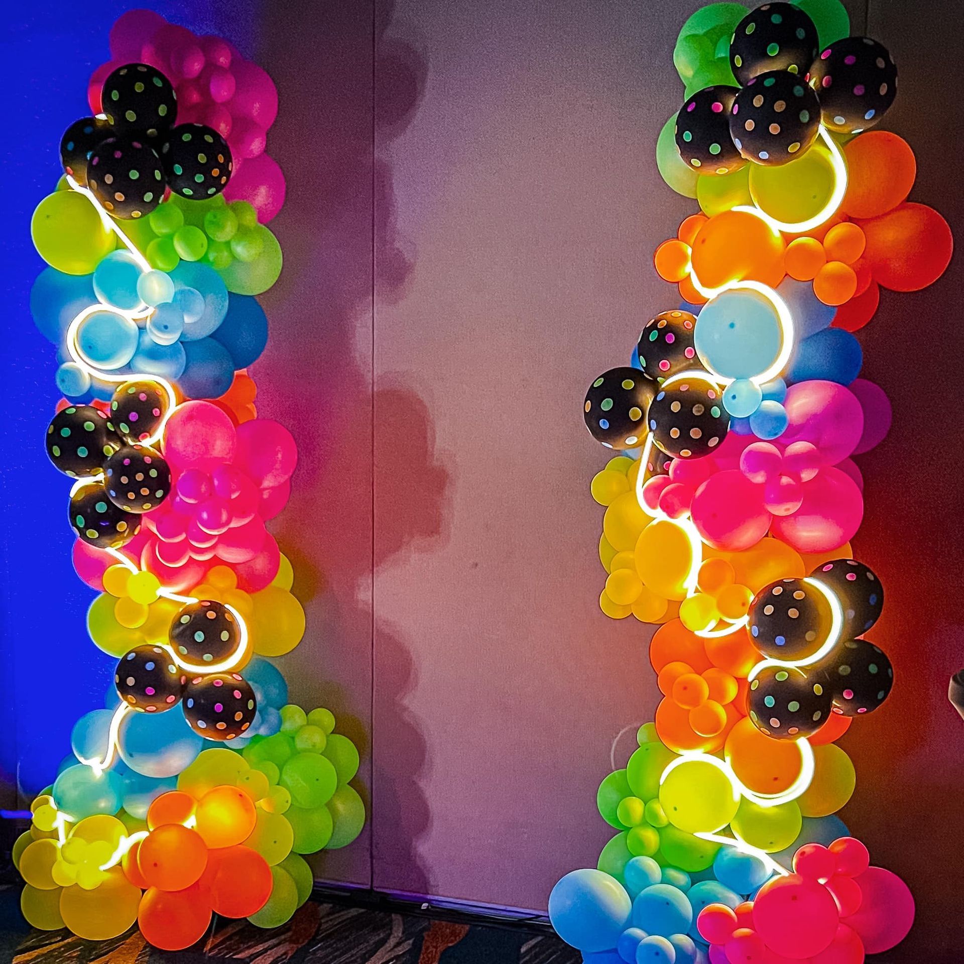 A bunch of colorful balloons are glowing in the dark