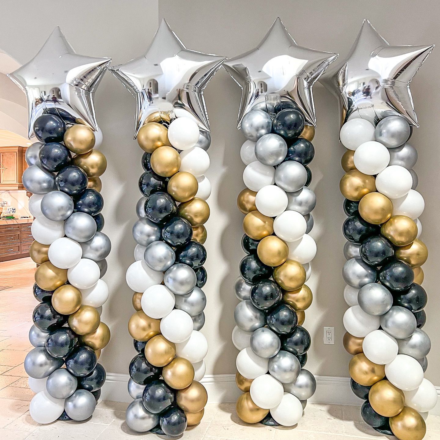 Three columns of balloons with stars on them are lined up in a room.