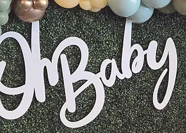 a sign that says `` oh baby '' is surrounded by balloons .