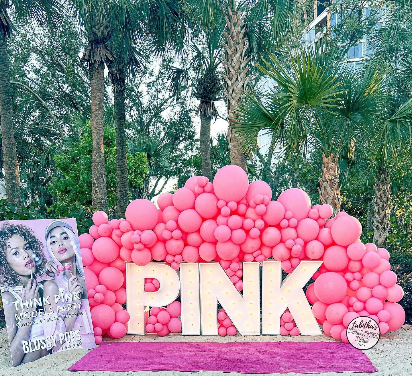 a wall of pink balloons with the word pink in the middle .