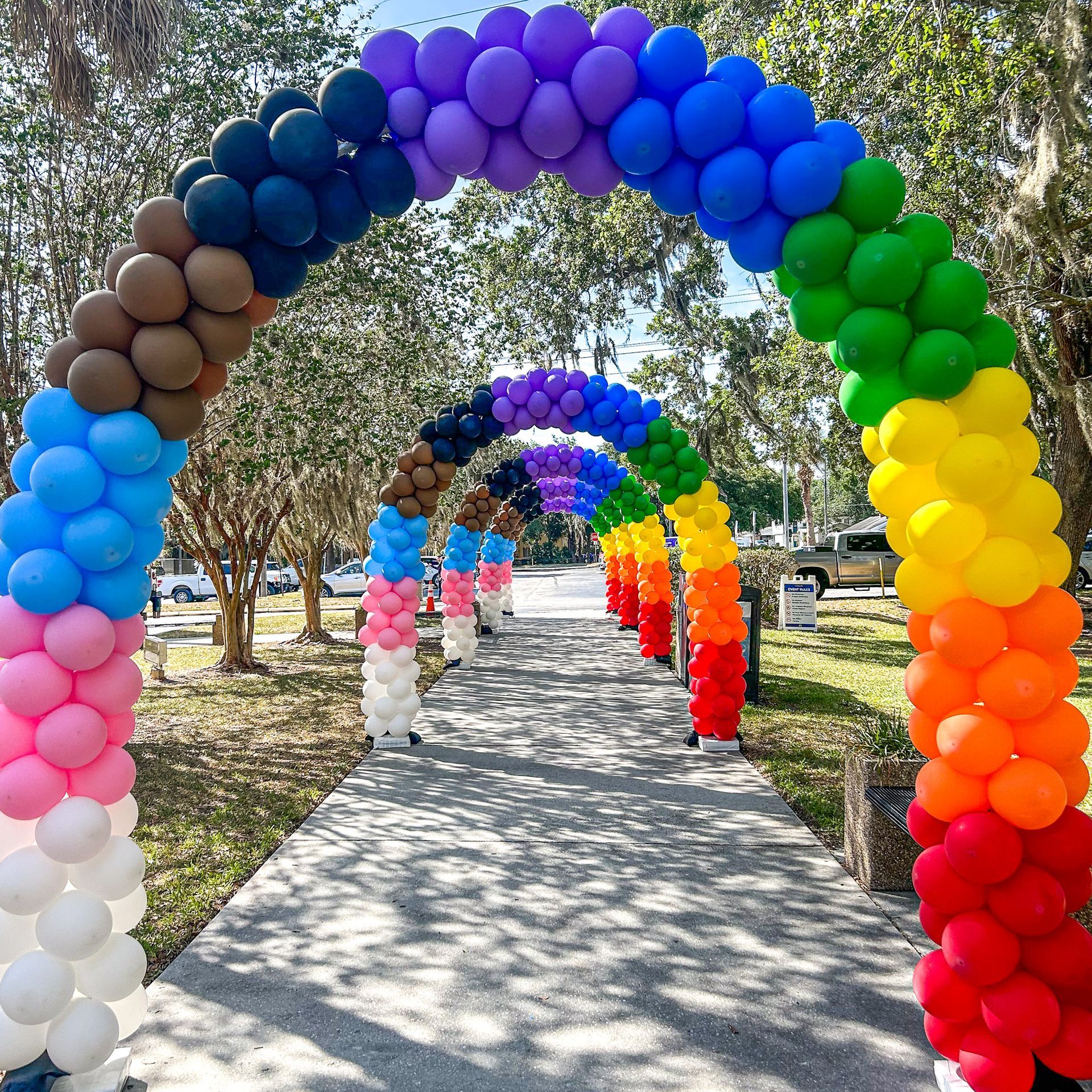 A row of colorful balloons are arranged in the shape of a rainbow.