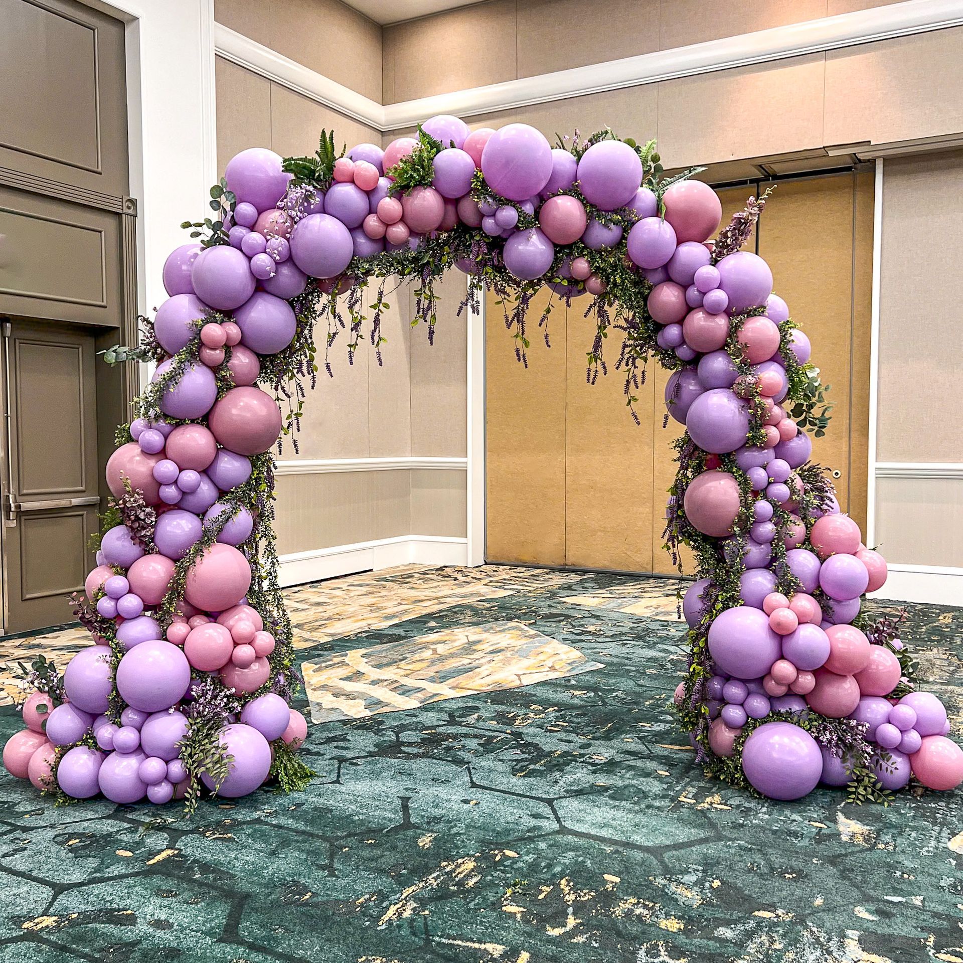 A room decorated with purple and pink balloons and flowers.