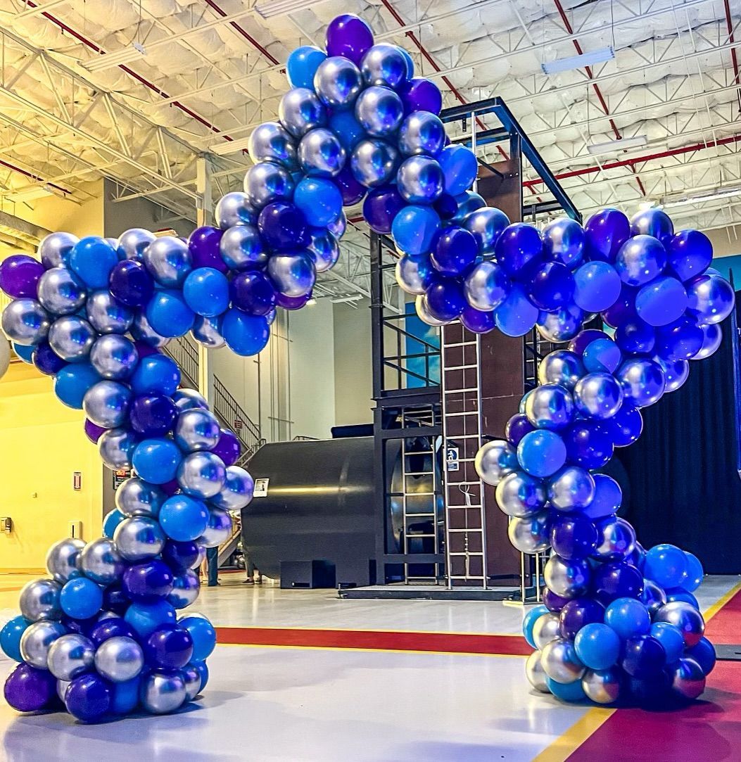 A large arch made of blue and purple balloons in a room.