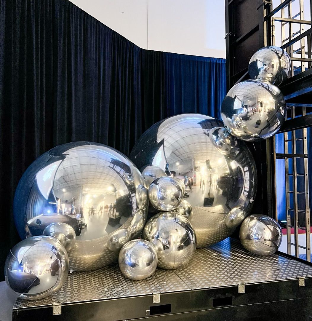 A bunch of silver balls are sitting on top of each other on a table.