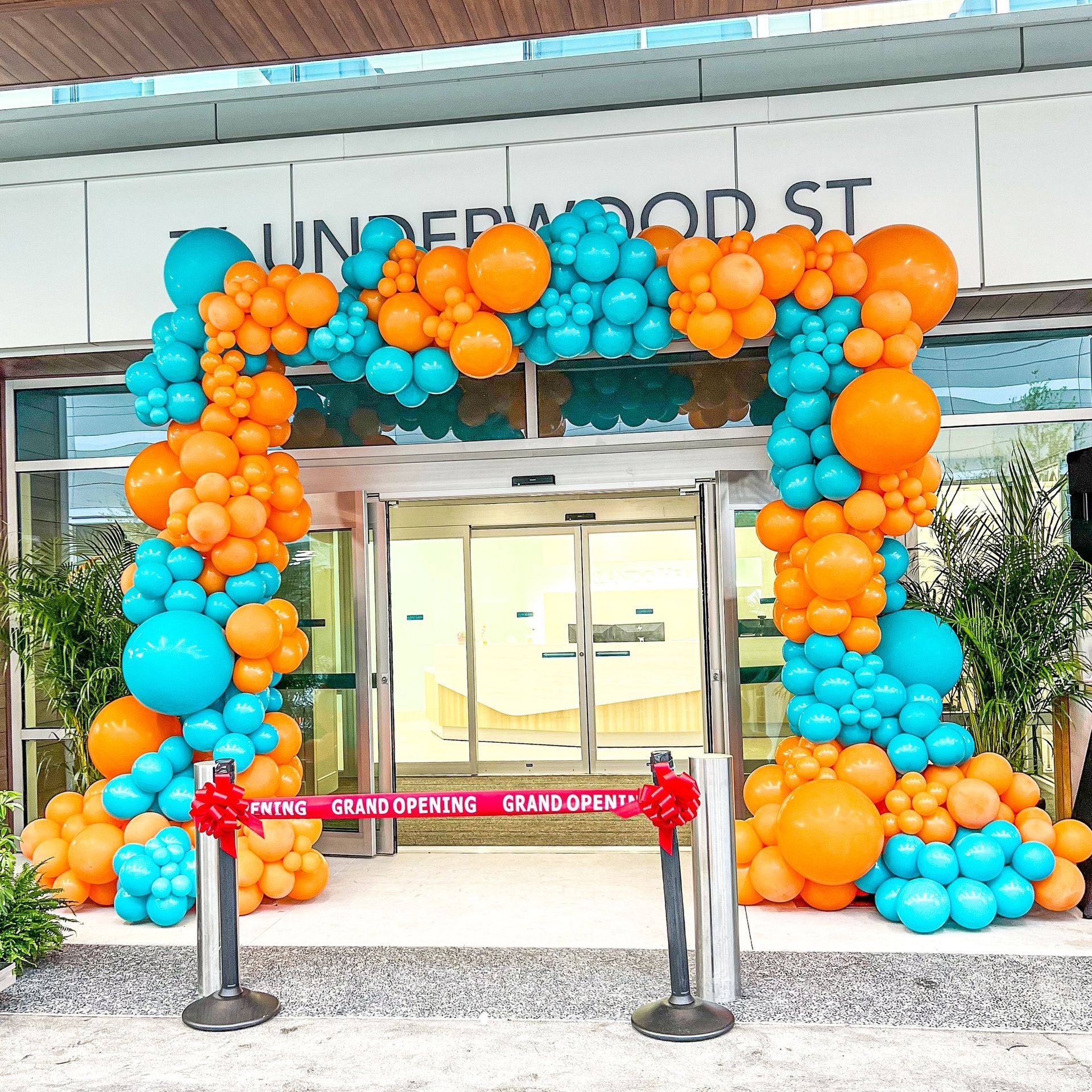 A large arch made of orange and blue balloons is in front of a building