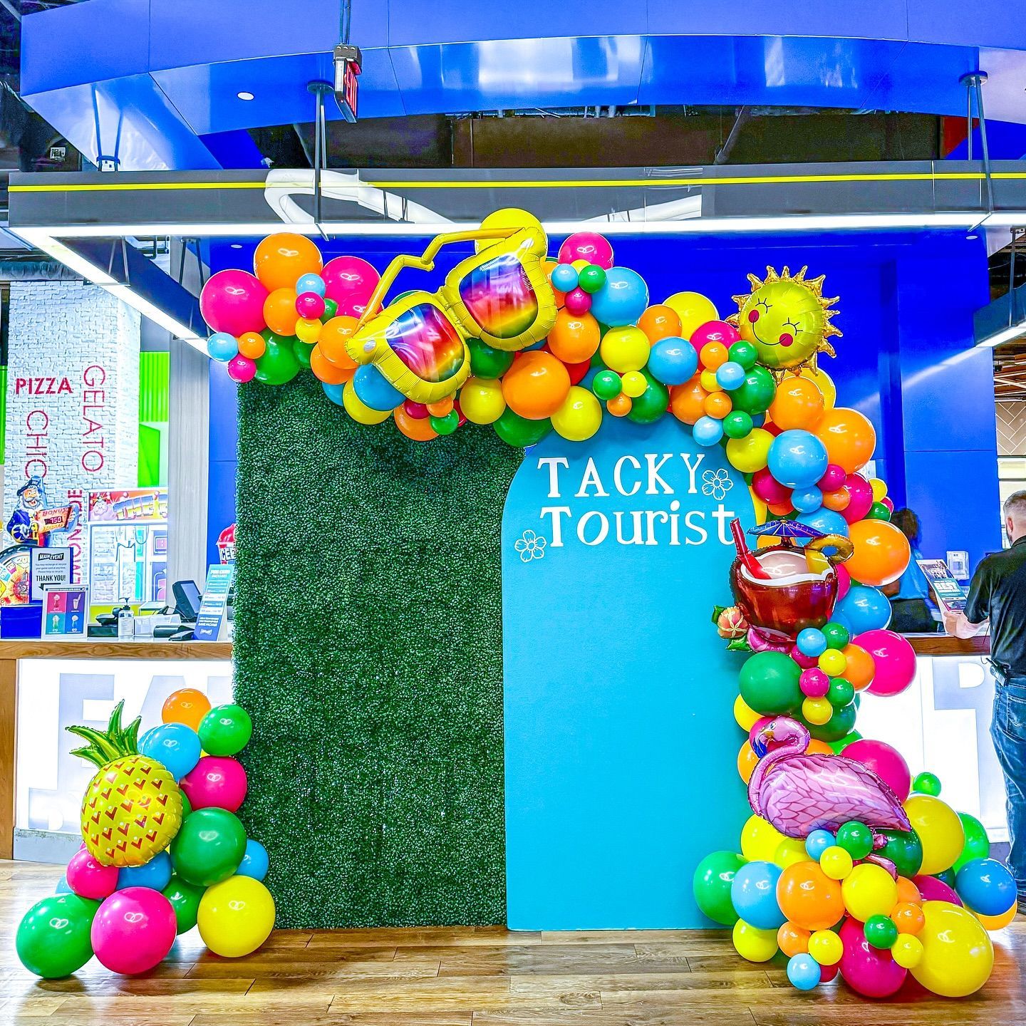 A bunch of colorful balloons are sitting on a wooden floor in front of a wall.