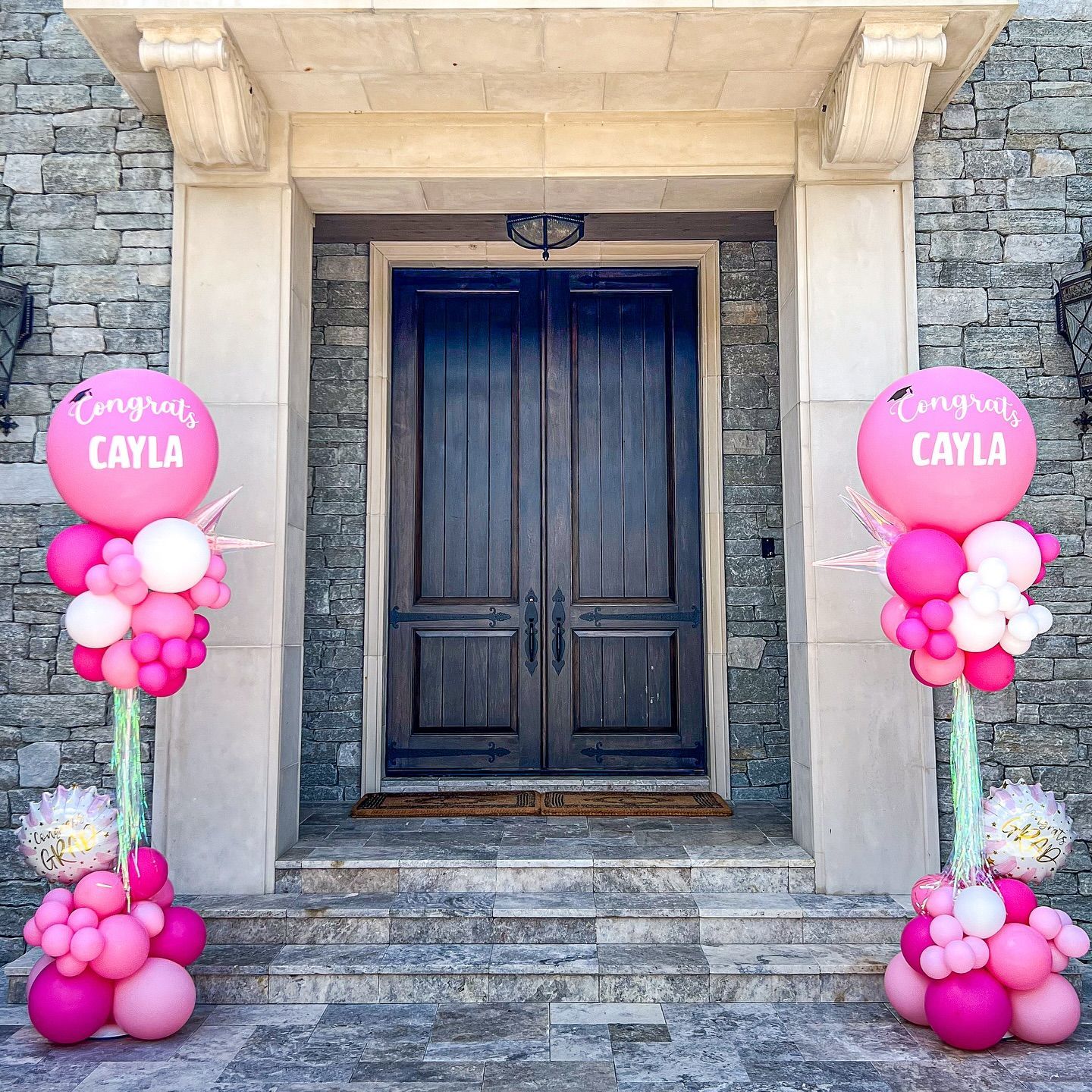 A couple of pink balloons that say congrats cayla on them