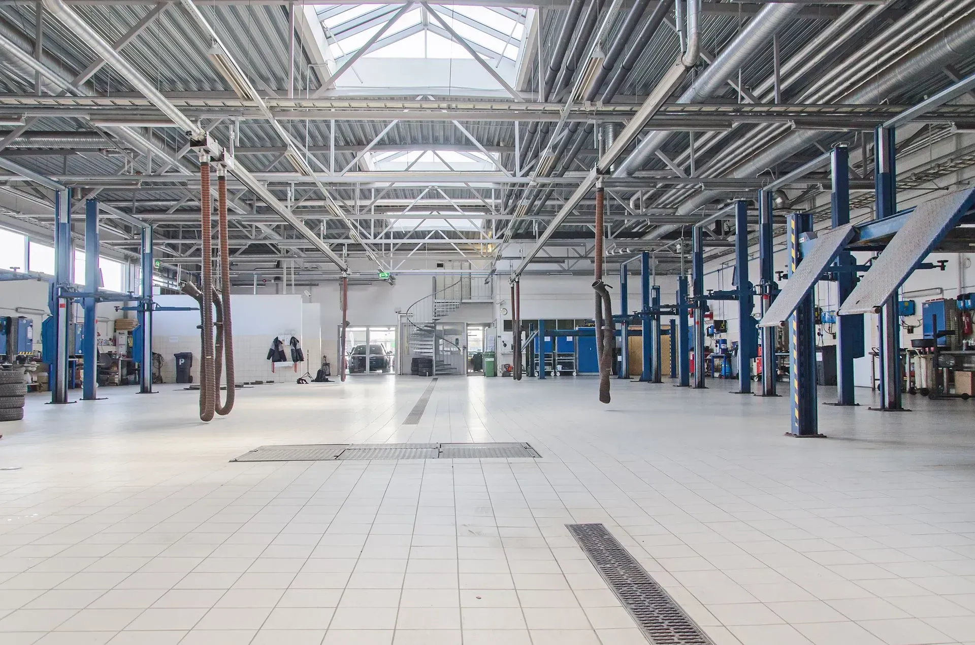 Large, empty auto repair shop with vehicle lifts and overhead lighting.
