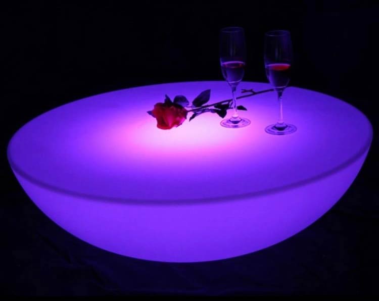 purple lit up table with cocktails and red rose