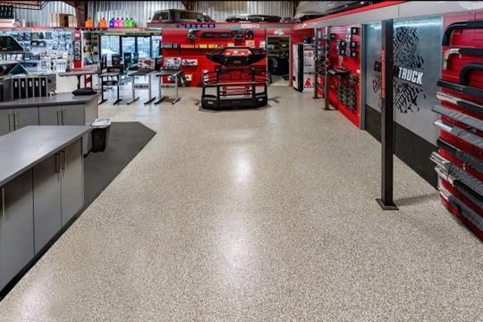 Interior view of a store with automotive parts on display, red and gray accents, speckled floor.