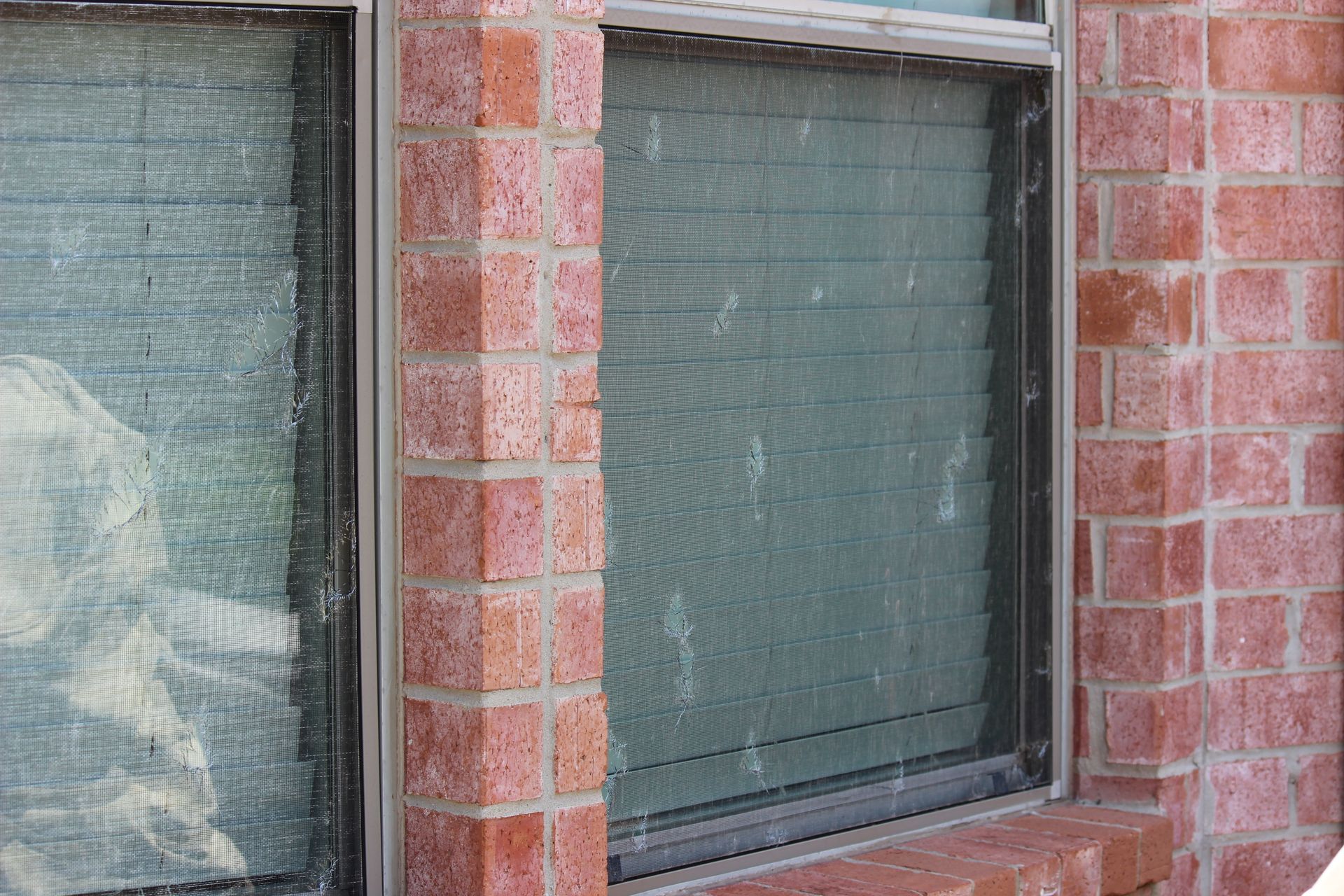 A brick building with a window and blinds on it.