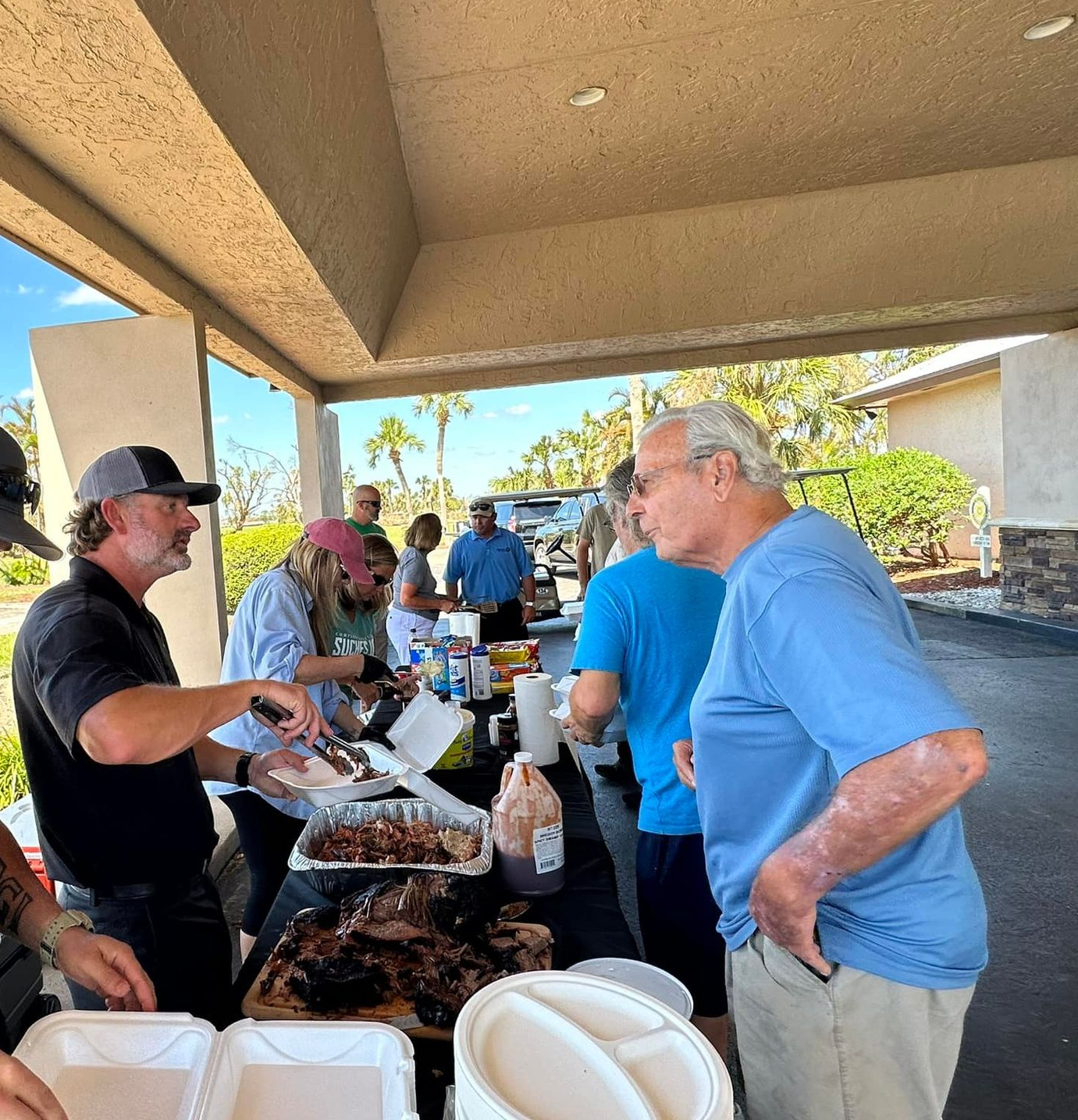 Man holding sign in front of a house. Sign promotes roofing service. Green lawn, blue sky.