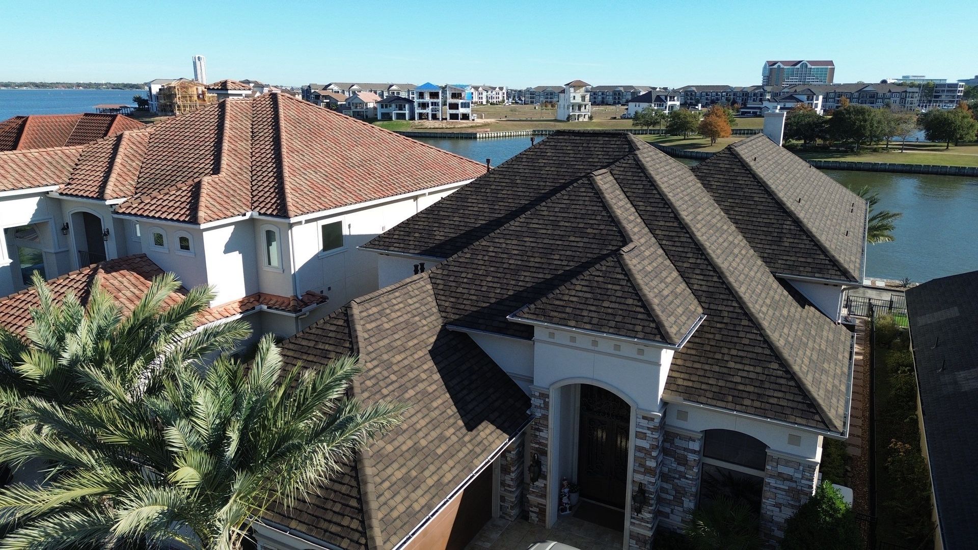 A residential building with a green roof, white-framed windows, under a blue sky with fluffy clouds.