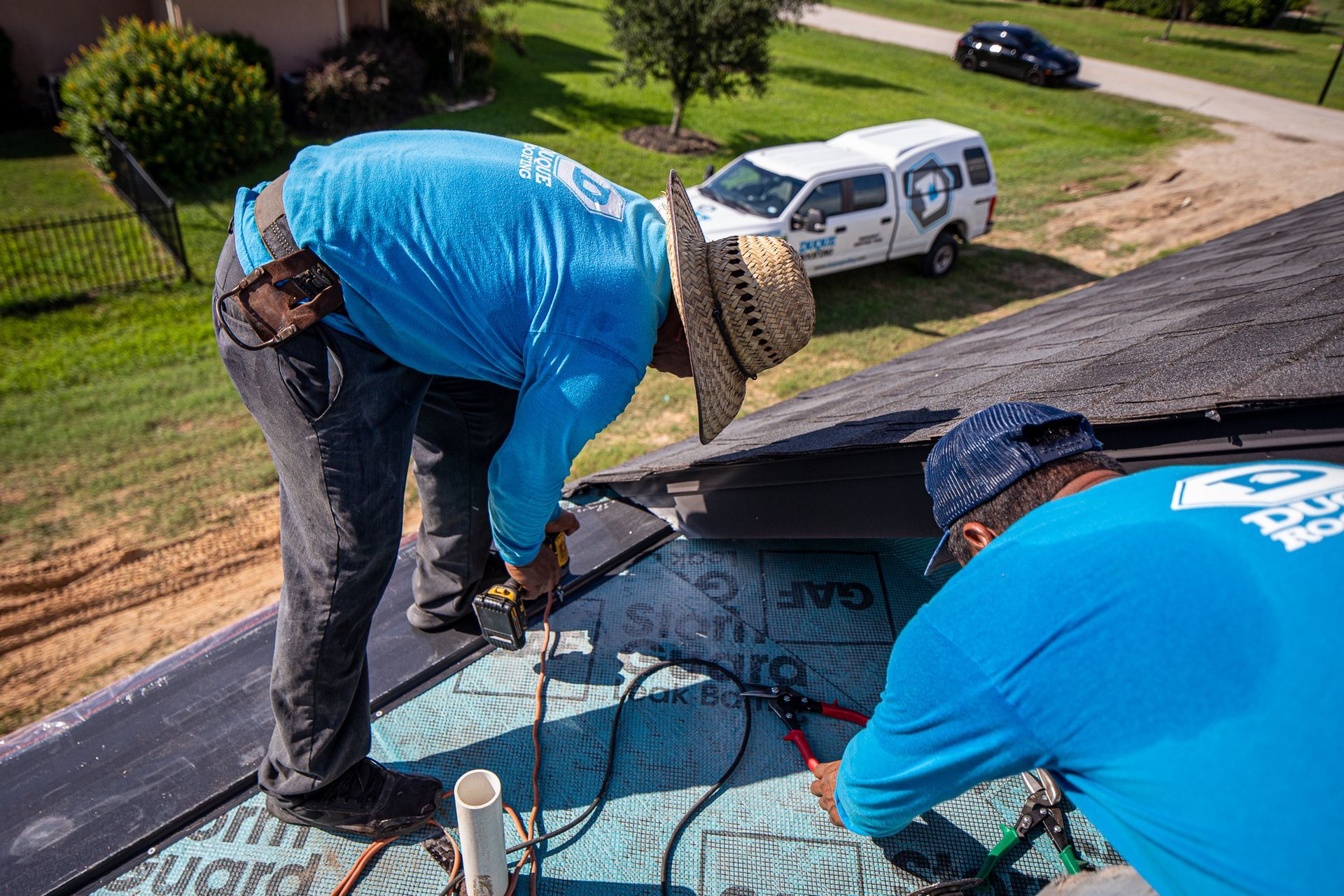 White corrugated metal roof with vent, trees, and blue sky with clouds.
