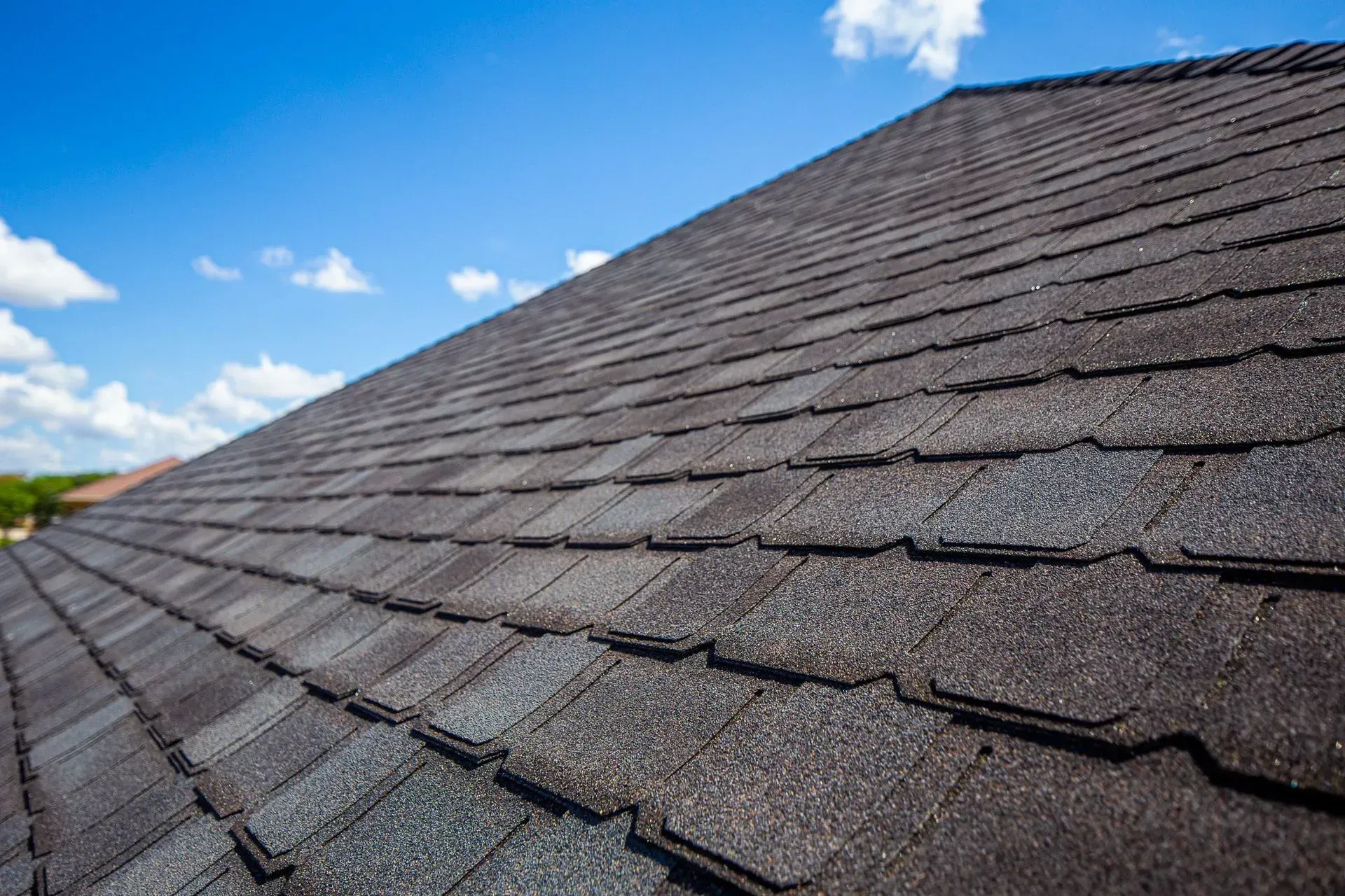 A brick home with a dark shingled roof under a clear blue sky.