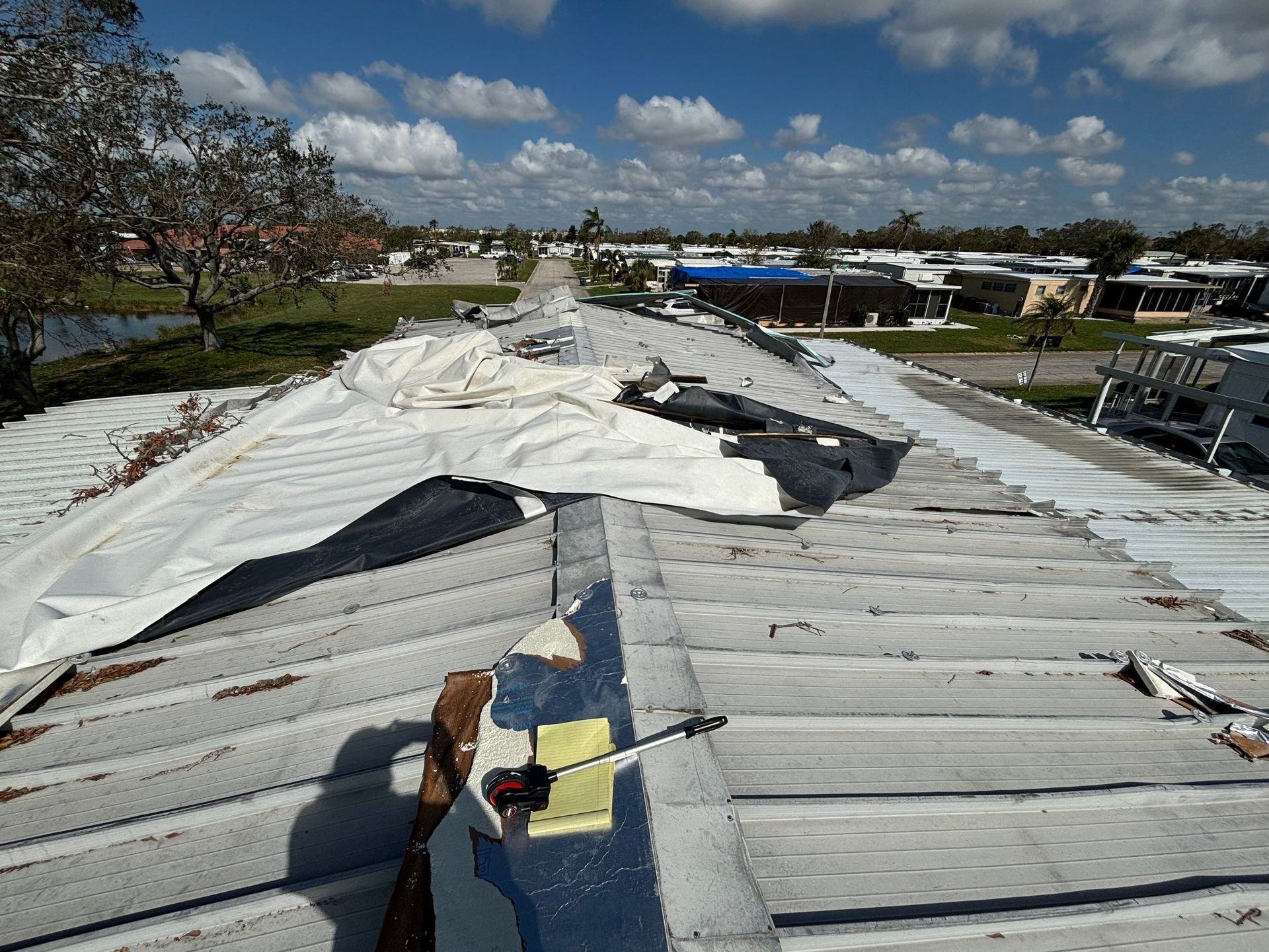 Close-up view of a dark gray composite roof against a blue sky with scattered clouds.