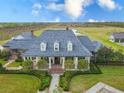 Large house with gray roof, white columns, and green lawn.