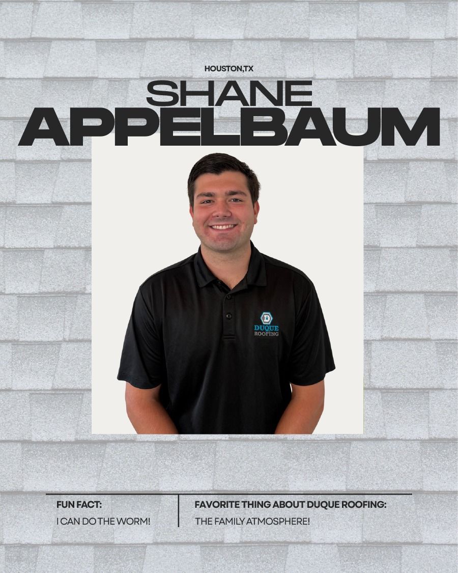 Shane Appelbaum smiling, wearing a black shirt with logo. Headshot on gray roof background.