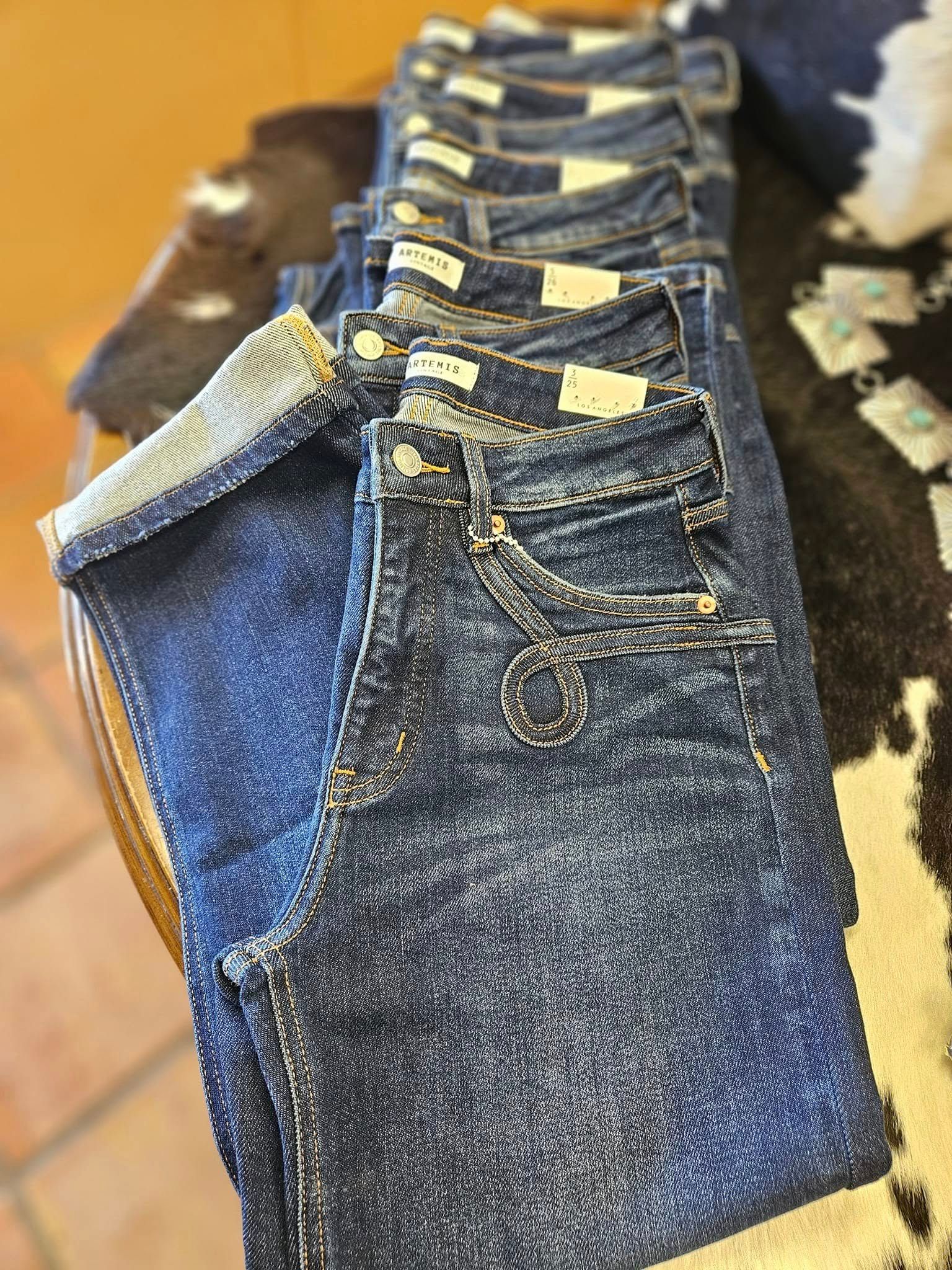 A row of jeans sitting on top of a cowhide rug.