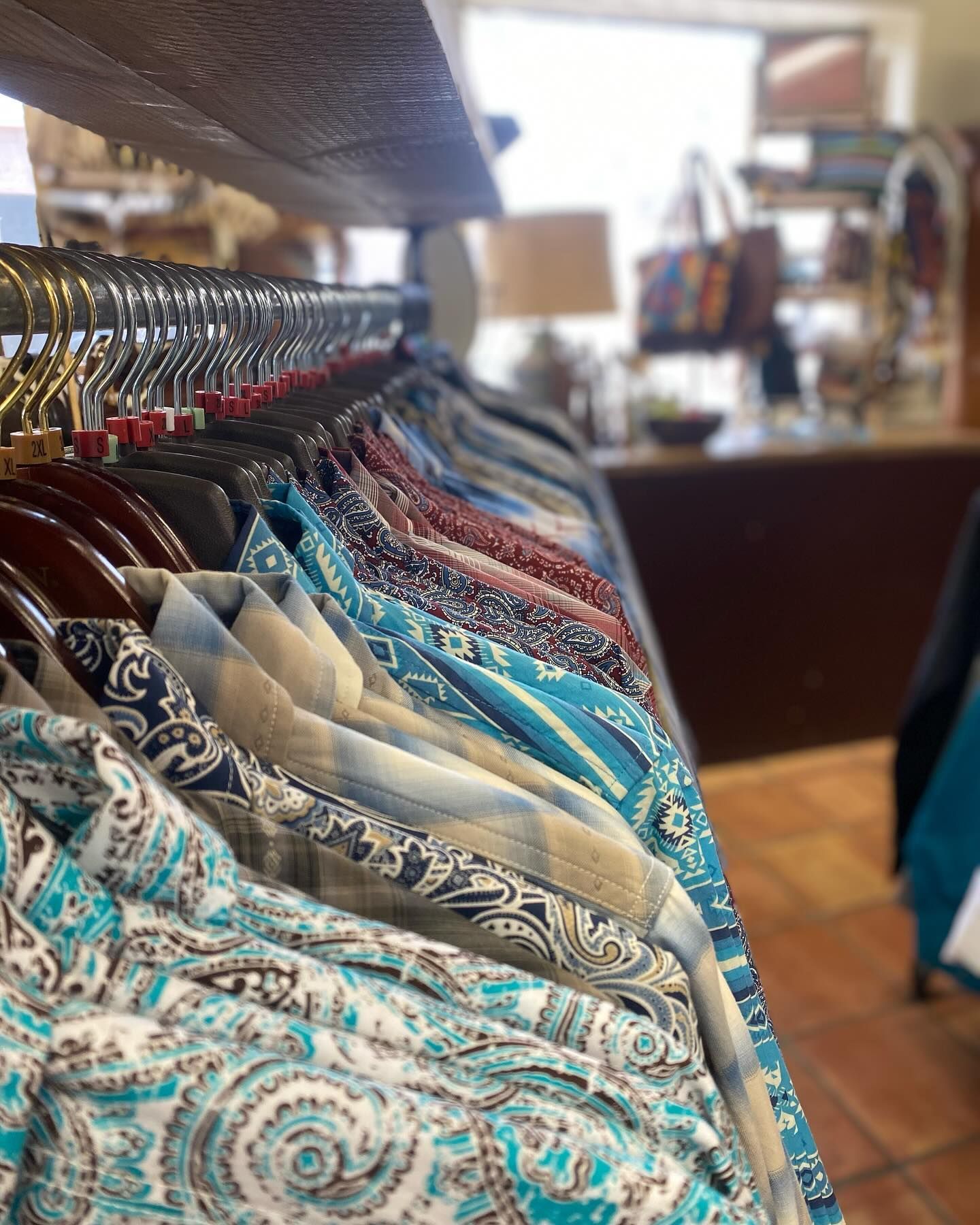 A row of shirts hanging on a rack in a store.