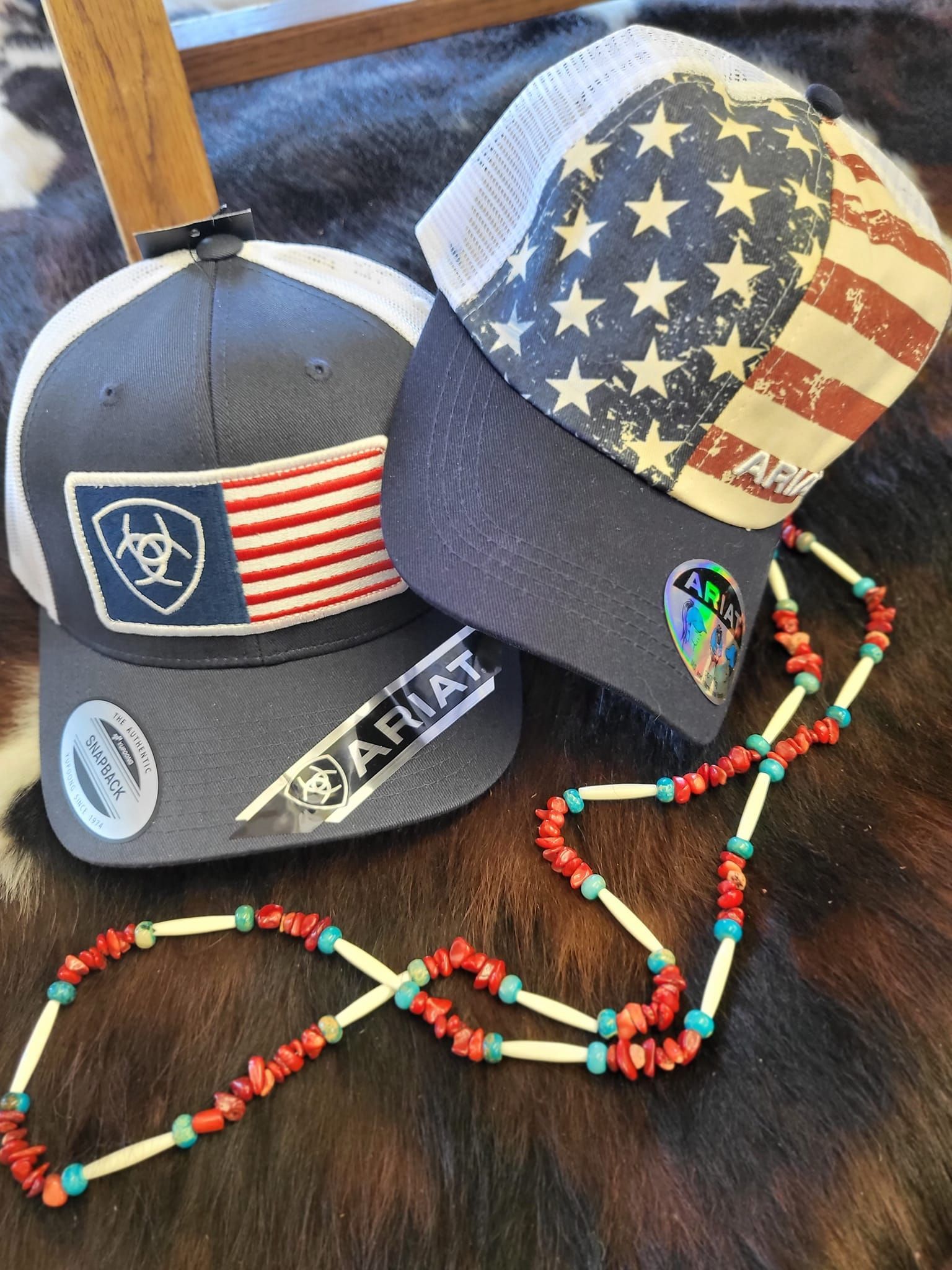 Two hats and a necklace are sitting on top of a cowhide.