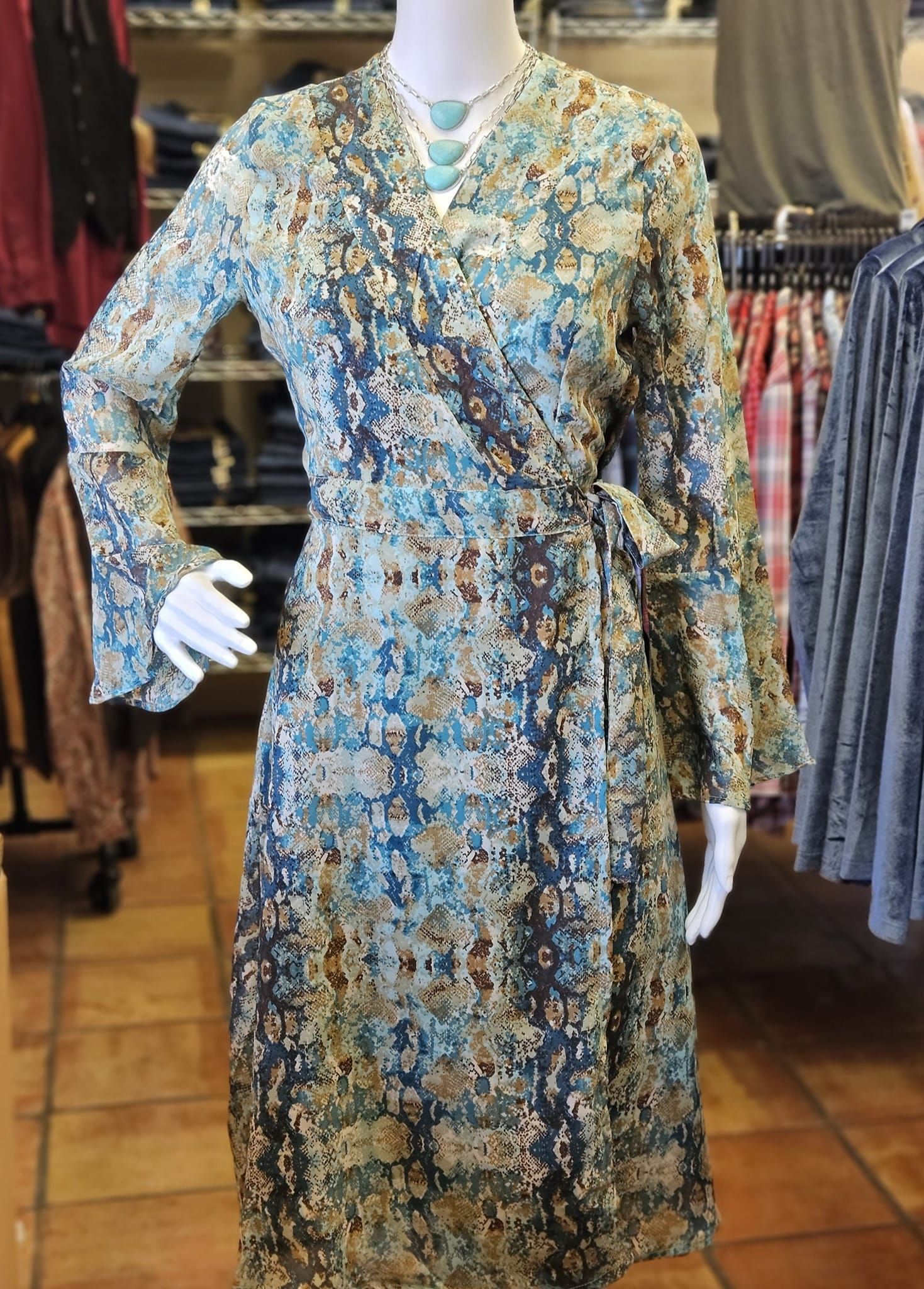 A mannequin is wearing a blue wrap dress in a store.