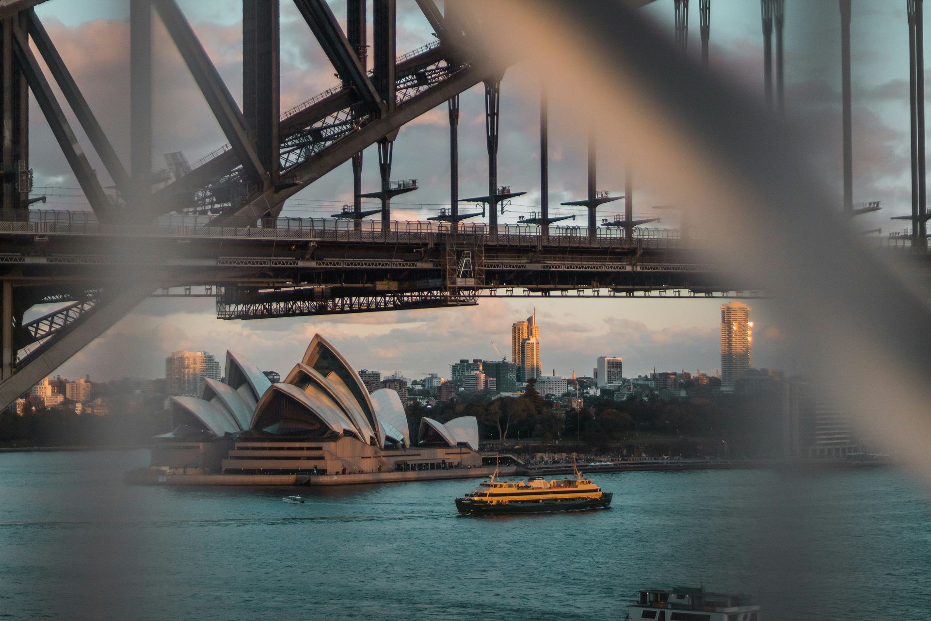 A boat is going under a bridge in sydney.
