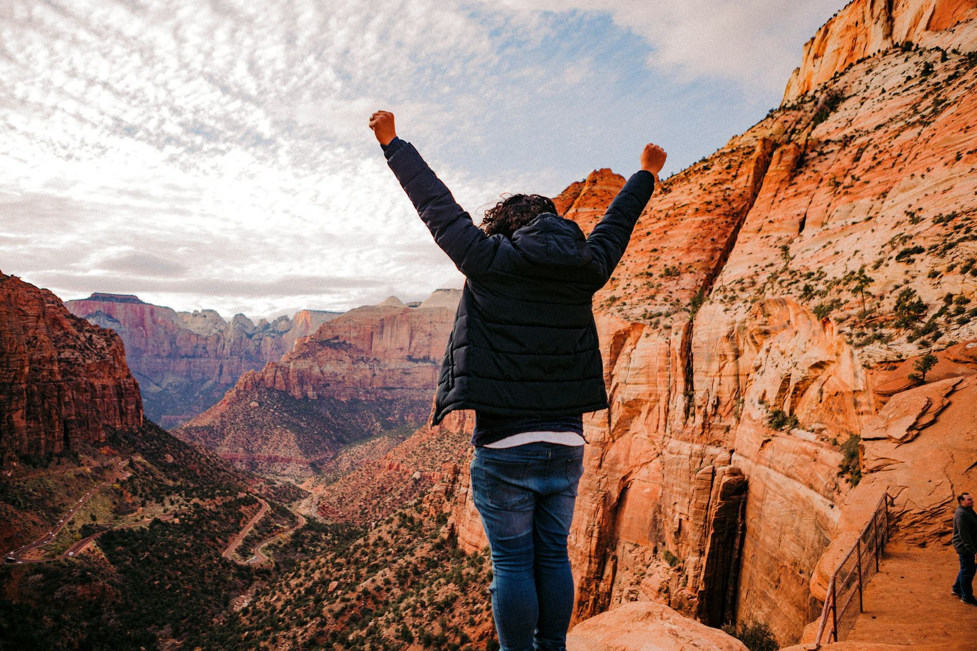 A man is standing on top of a mountain with his arms in the air.