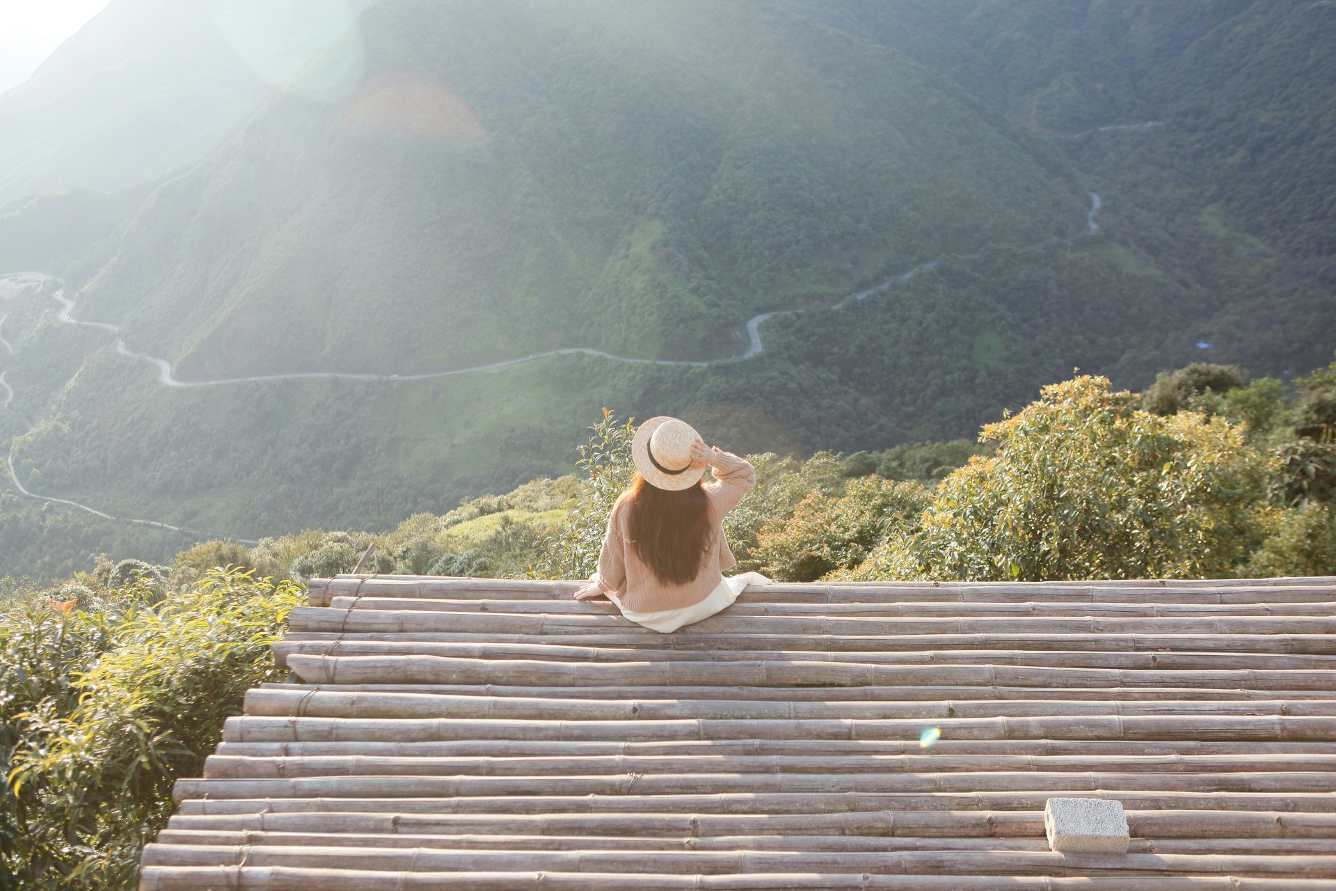 A woman is sitting on a wooden deck overlooking a mountain.