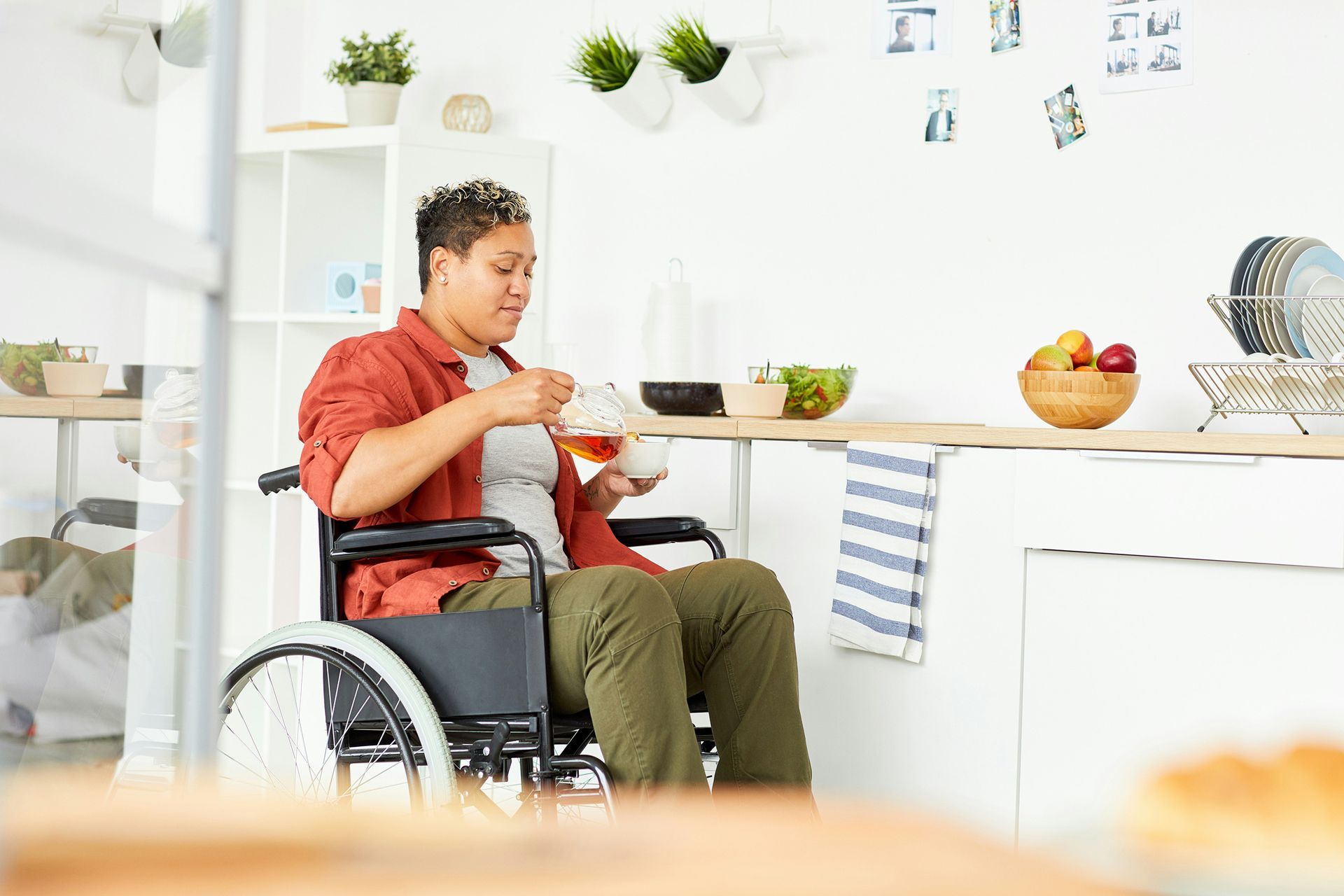 A woman in a wheelchair is sitting at a table eating food.