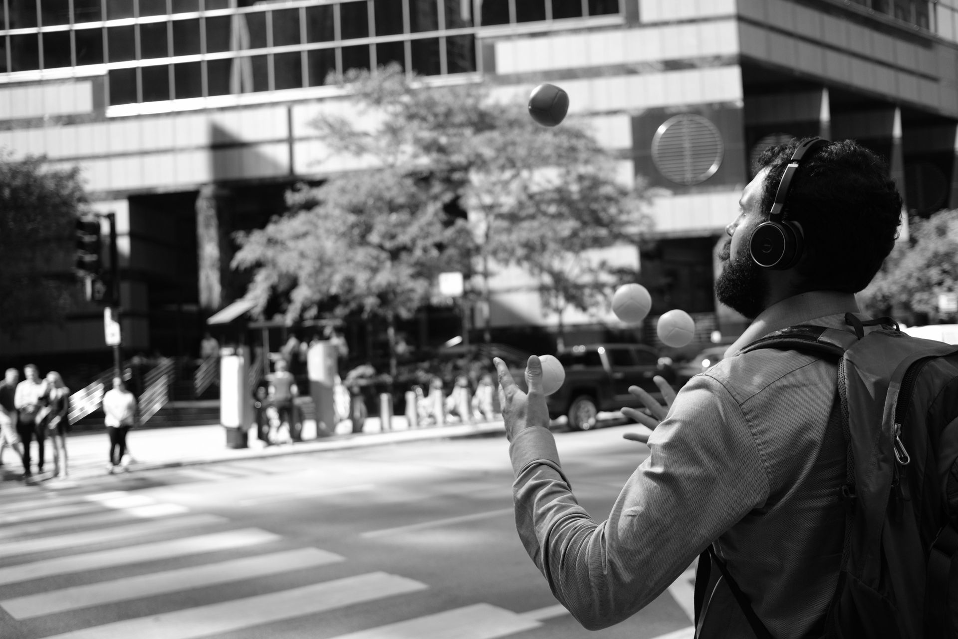 A black and white photo of a man throwing balls in the air.
