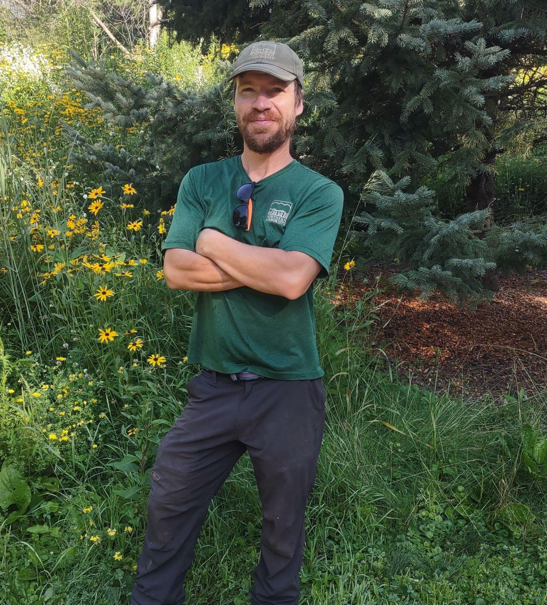 A man with a beard wearing a white shirt that says ' forest service ' on it