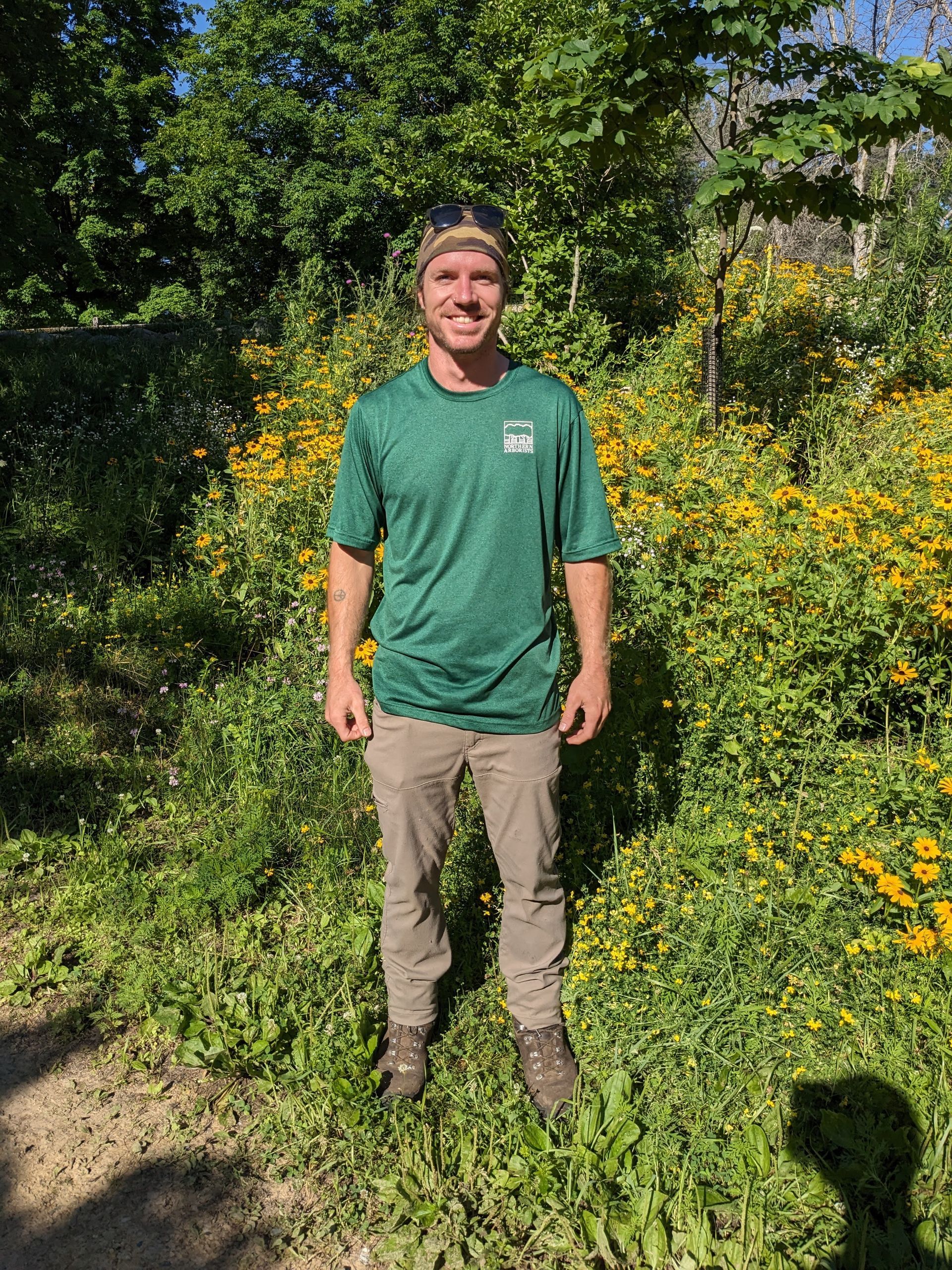 A man is standing next to a large log in the woods.