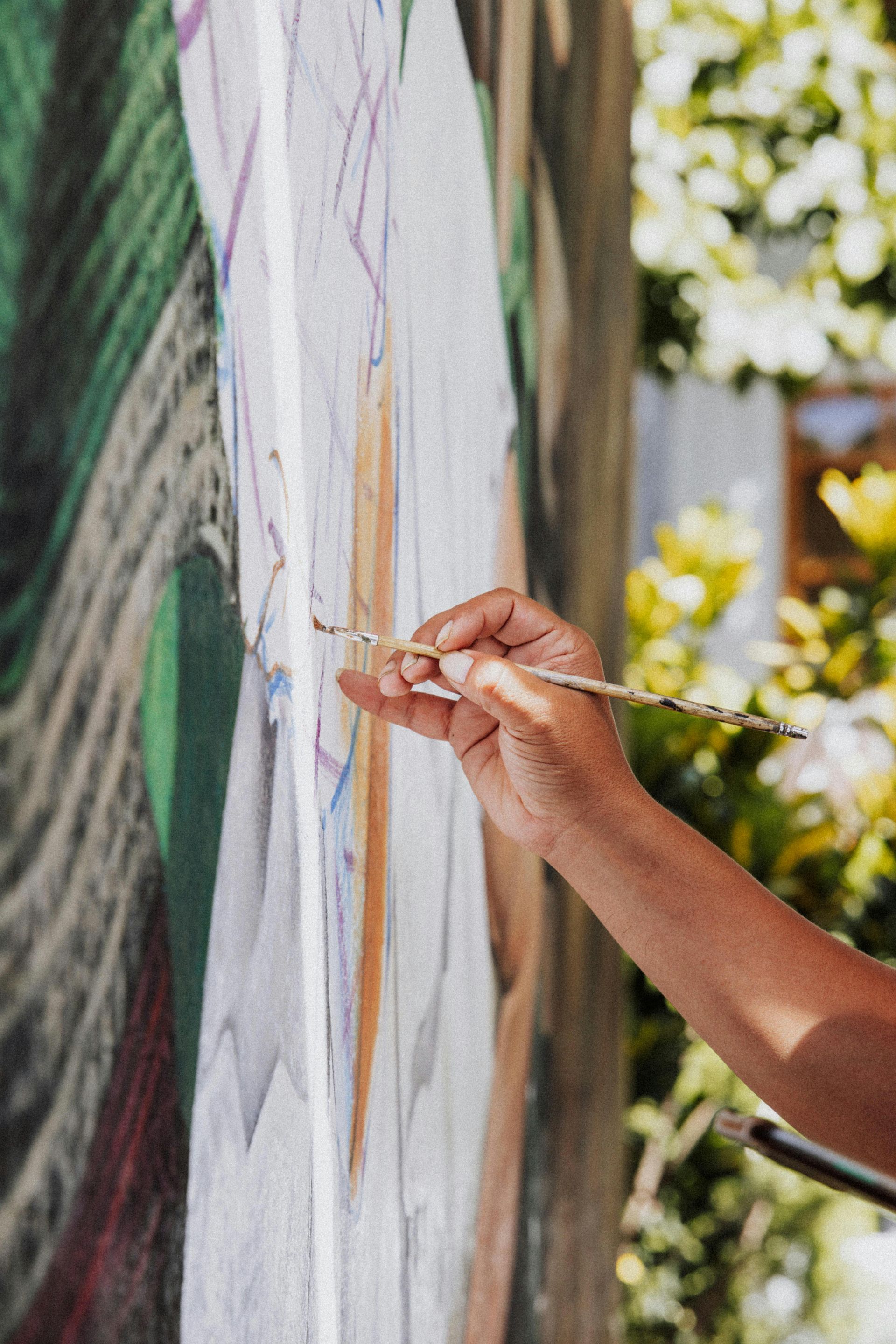 Met de hand een muurschildering maken op een groot doek in de buitenlucht met een kwast.