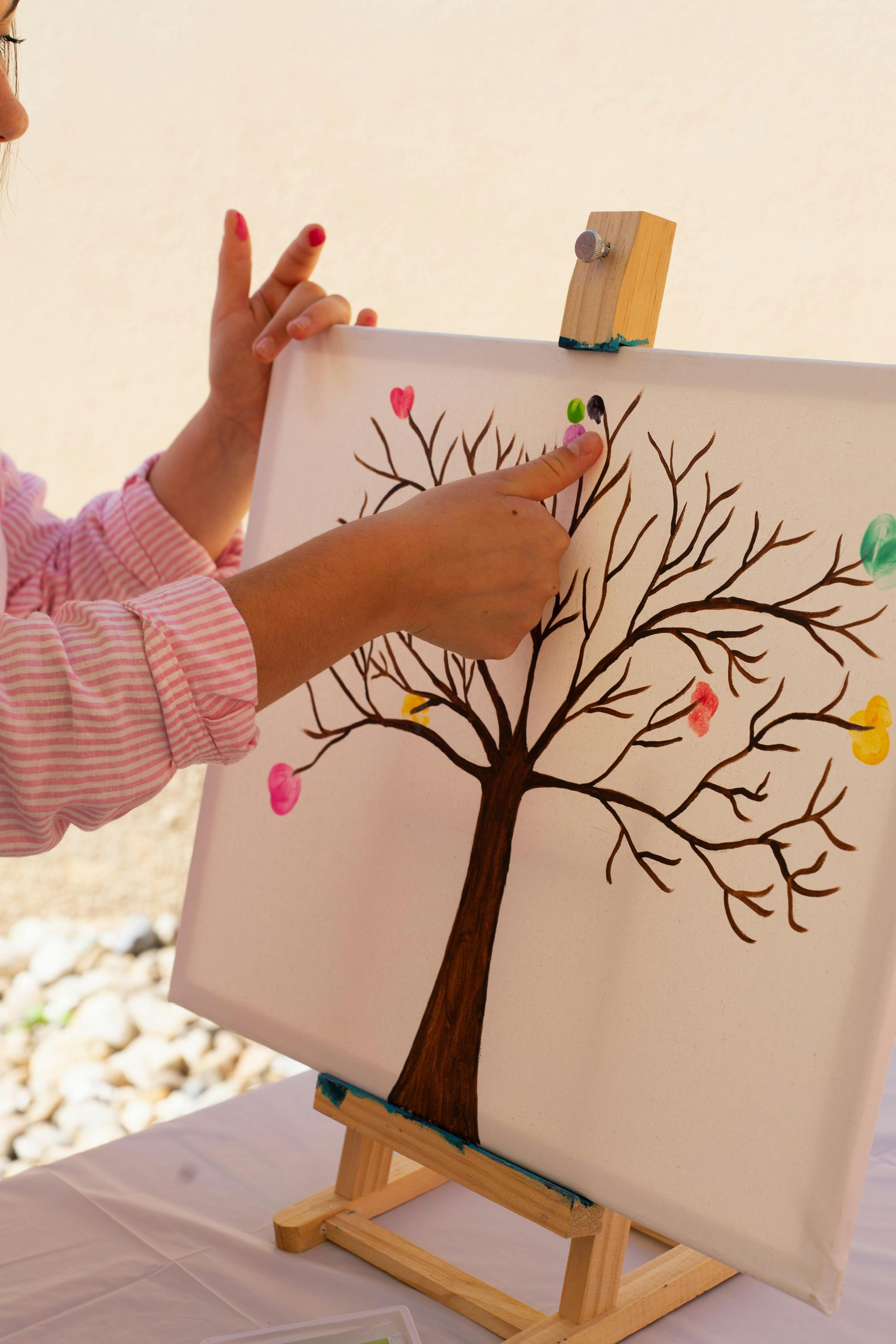 Handen schilderen een boom op een schildersezel met kleurrijke lentebloesems.