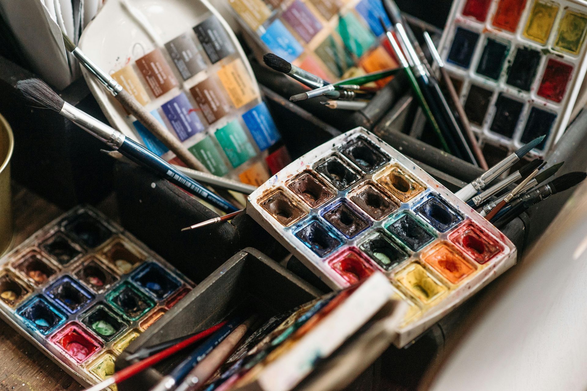 Open sets aquarelverf met diverse kleurrijke verfpanjes en penselen.