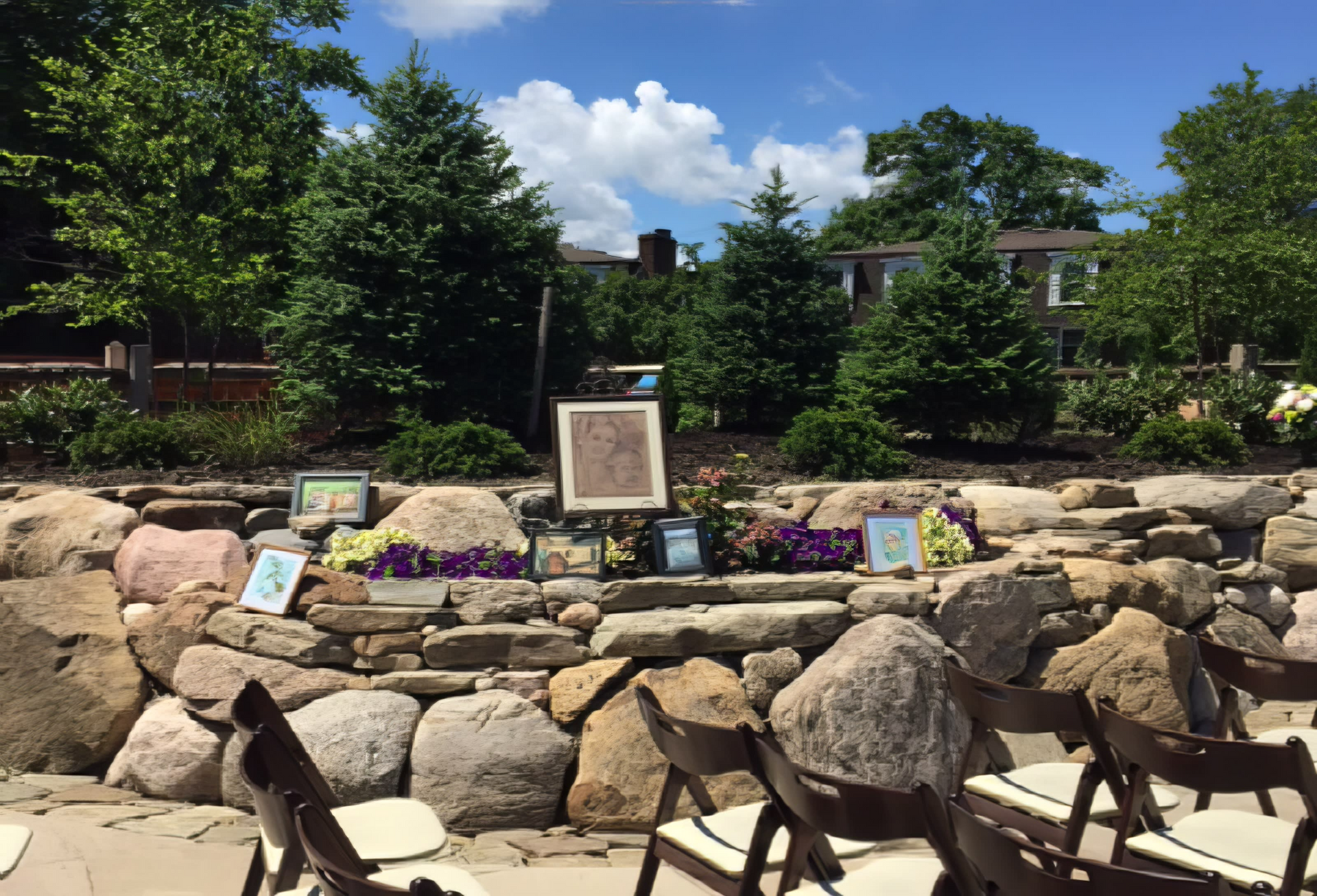 A row of folding chairs are lined up in front of a rock wall.