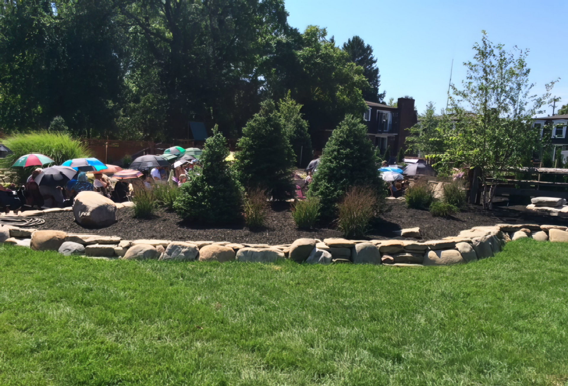A group of people are sitting under umbrellas in a park