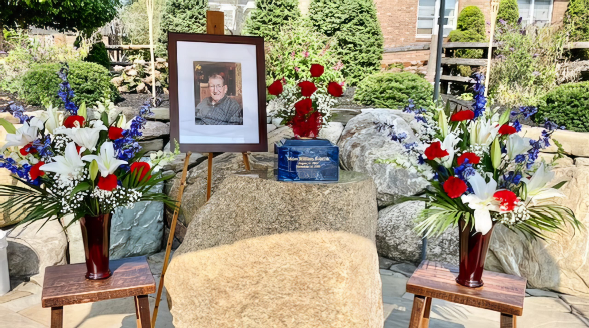 A memorial with flowers and a picture on an easel.