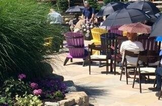 A group of people are sitting at tables under umbrellas on a patio.
