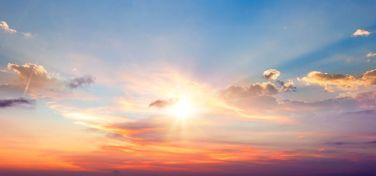 The sun is shining through the clouds at sunset.
