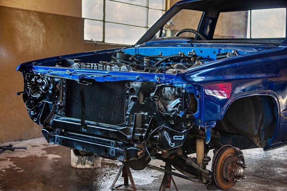 A Blue Car With the Engine Removed is Sitting on a Stand in a Garage — Stengels Crash Repairs In Garbutt, QLD