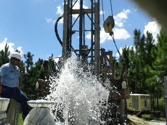 Two men are standing next to a large water pump.