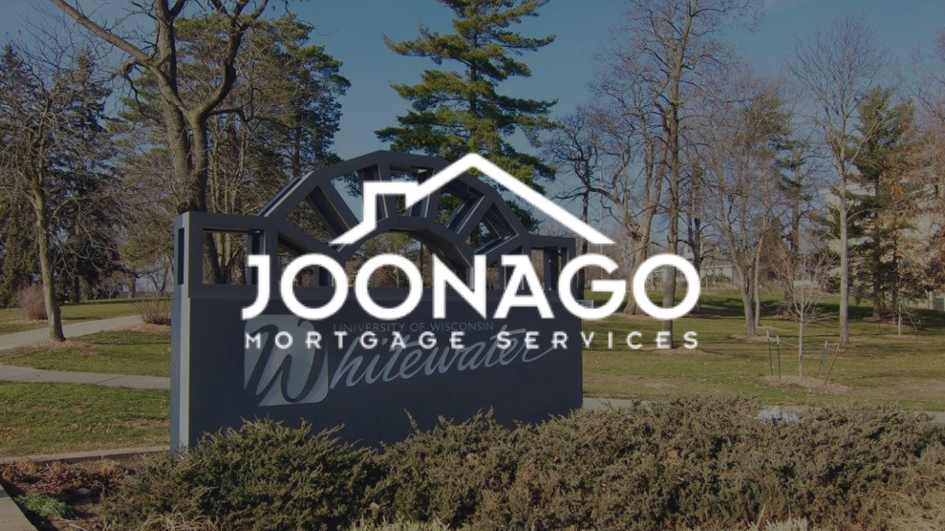 The logo for joonago mortgage services is on a whitewater wi sign in a park.