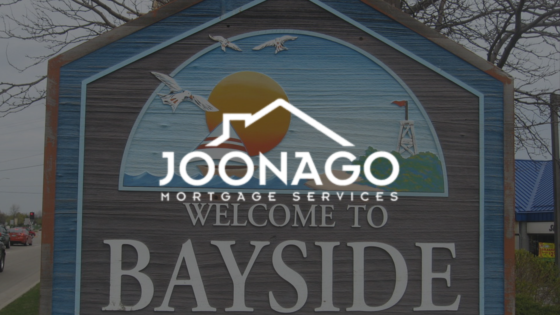 Sign welcoming visitors to Bayside with a Joonago Mortgage Services logo overlaid on it.
