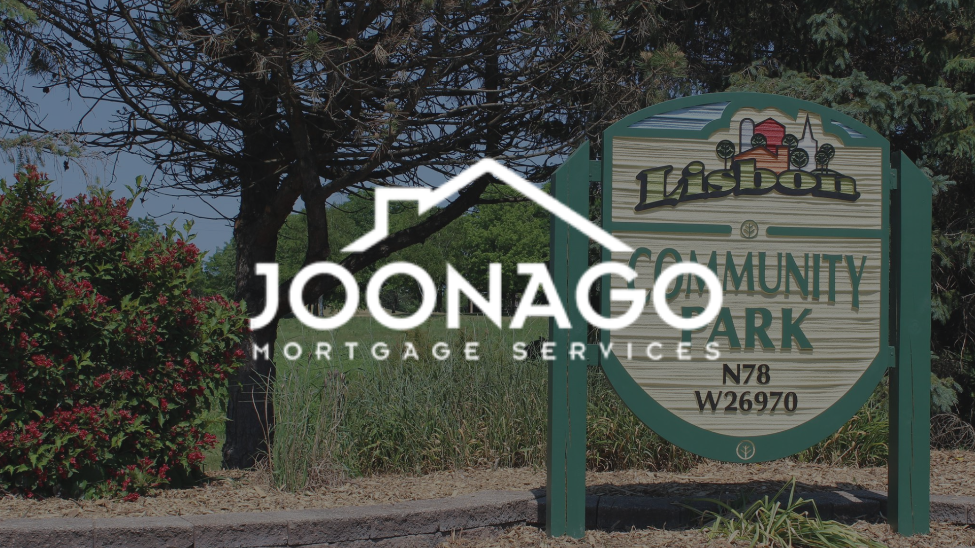 Joonago Mortgage Services logo over a sign for Lisbon Community Park, with trees and bushes in the background.