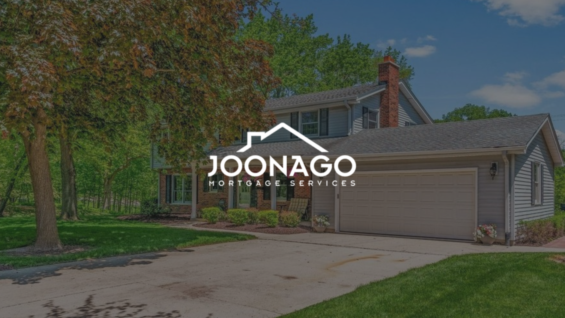 A house with a garage and trees in front of it.