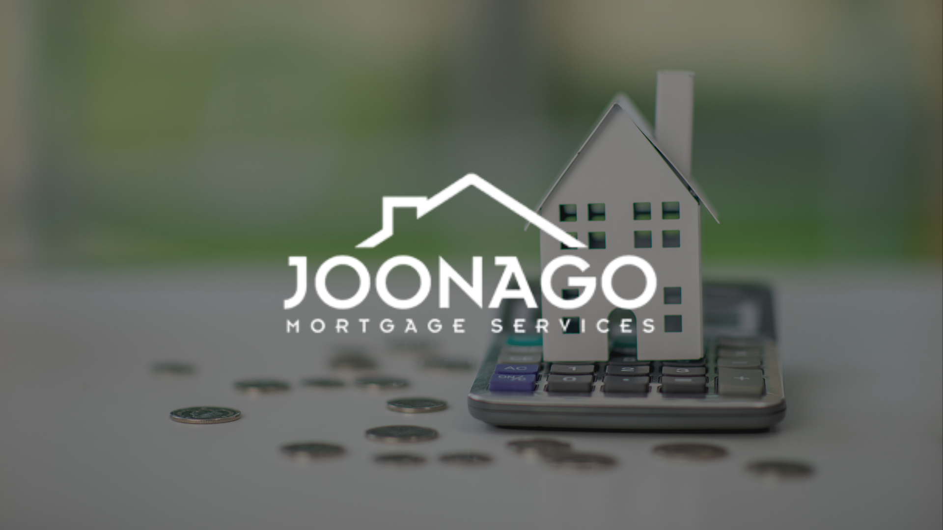 A model house is sitting on top of a calculator with joonago mortgage services logo on top