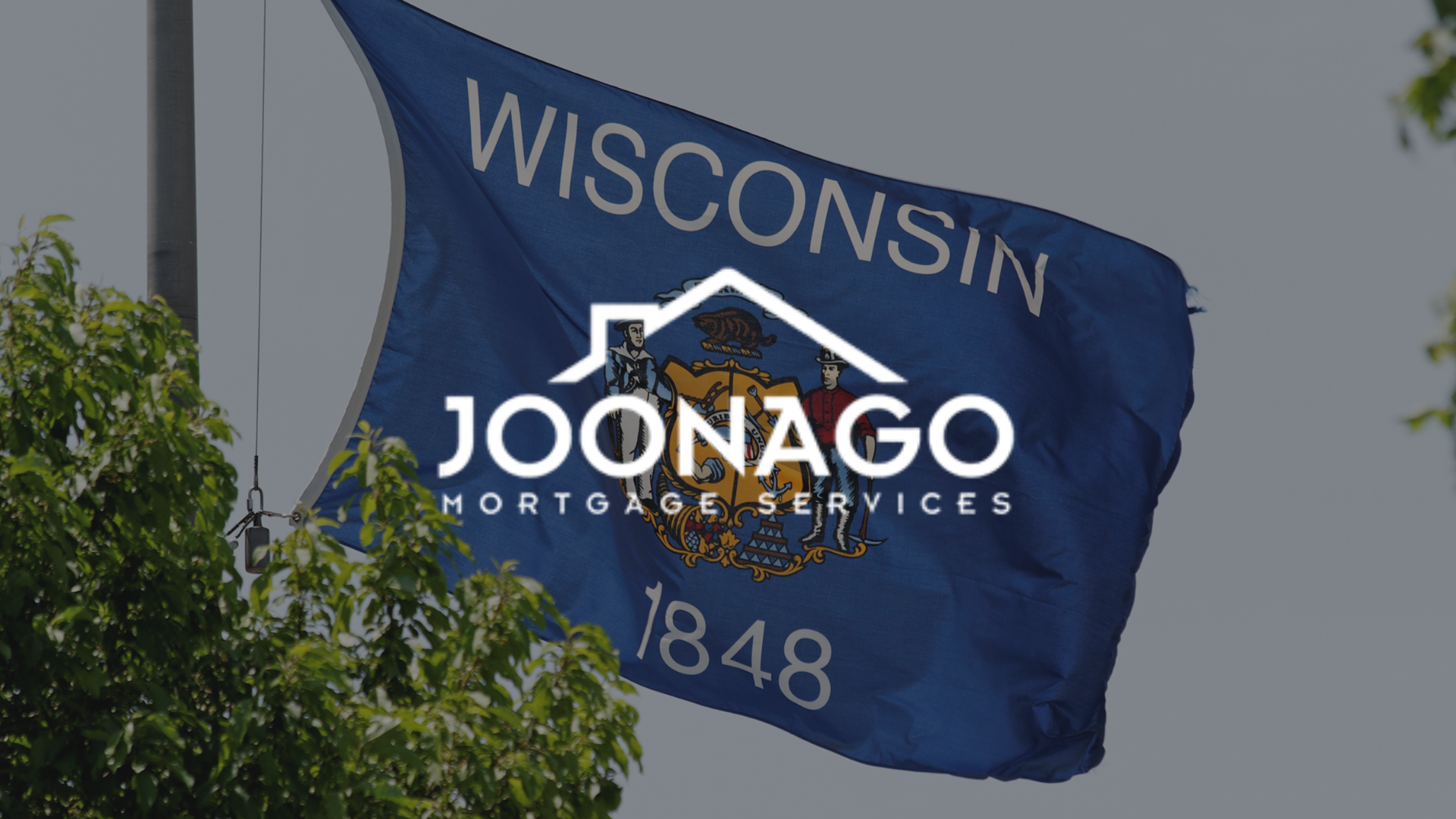 A large brick house with a logo for joonago mortgage services in front of it.
