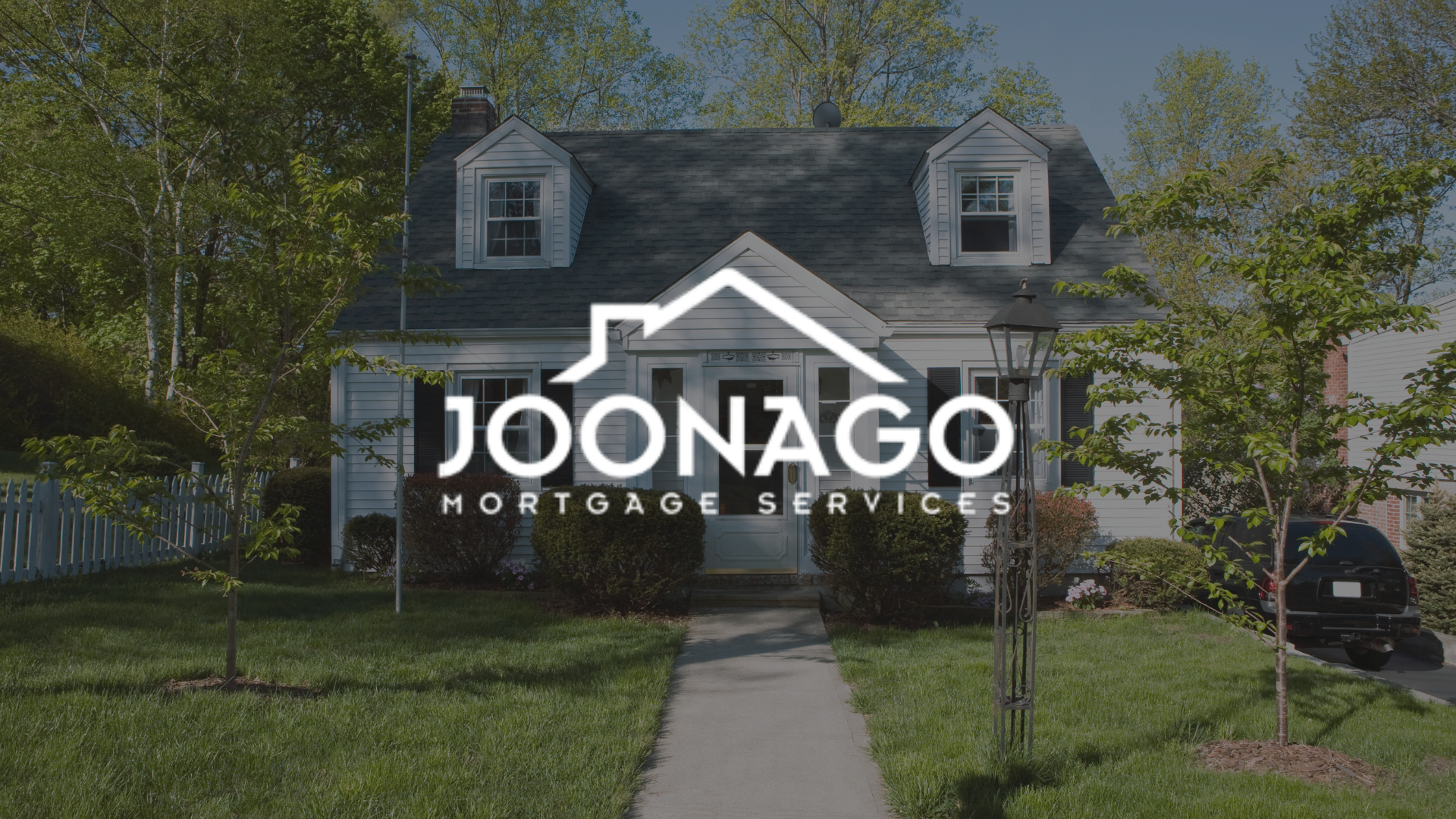A large brick house with a logo for joonago mortgage services in front of it.